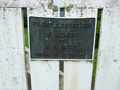 Bronze plaque attached to white wooden gate