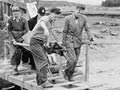 Men carrying body over bridge